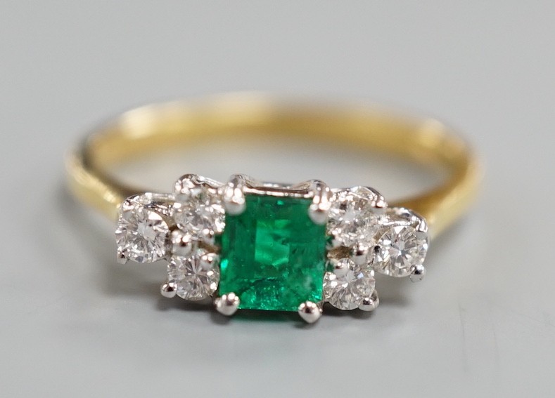 A modern 18ct gold and single stone emerald ring, with six stone diamond set shoulders, size N, gross weight 3.2 grams